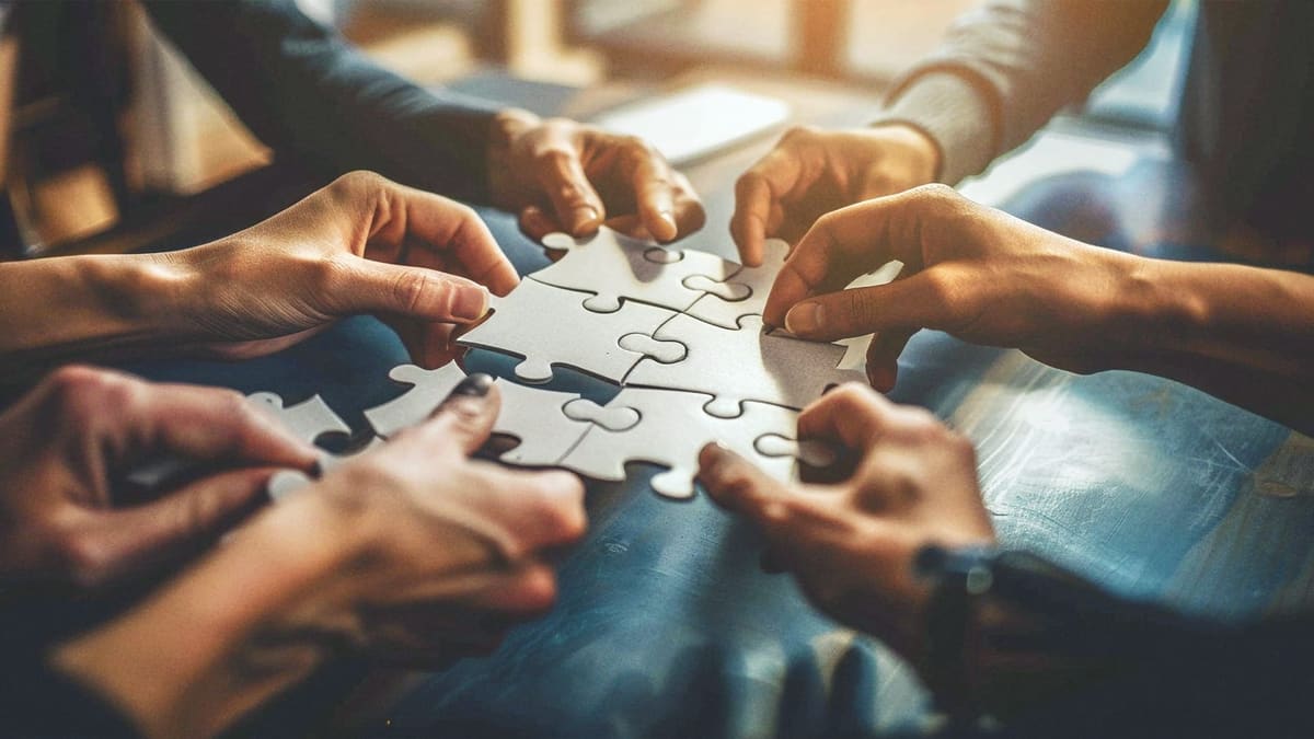 Hands fitting puzzle pieces together on a table